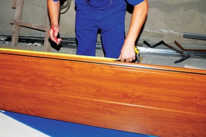 man measuring stained wood panel for installation