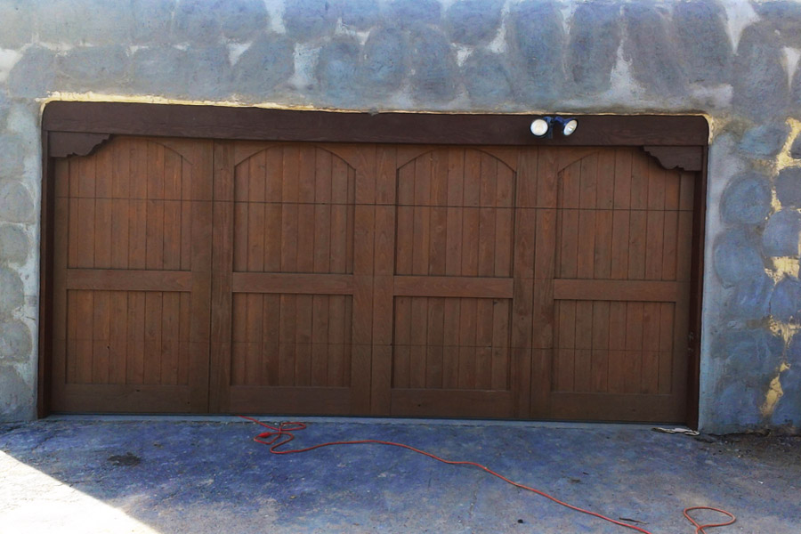 wide dark stained wood garage door on stone building