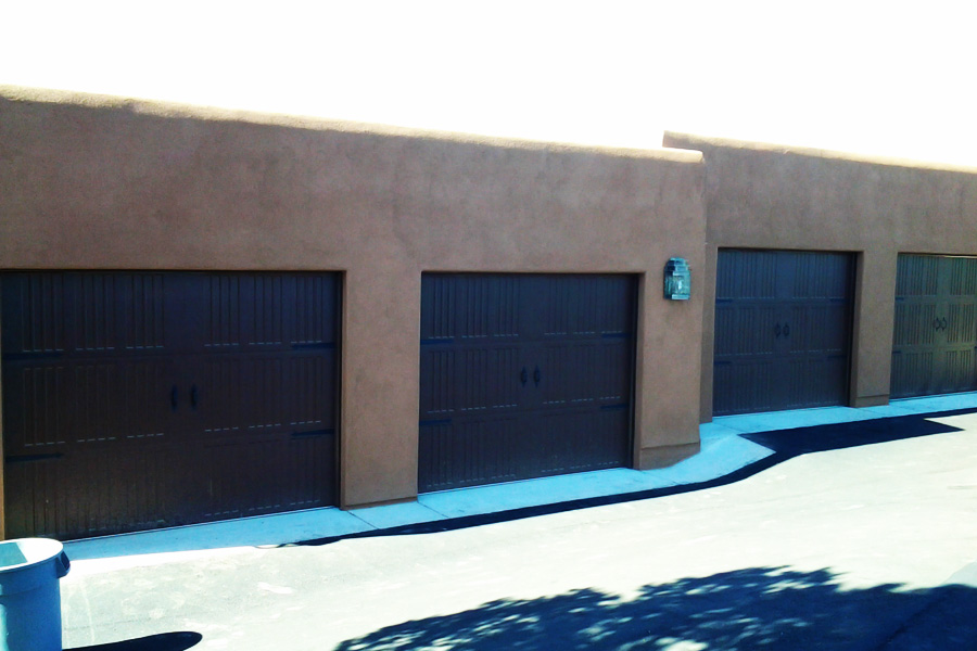 four dark wood stained garage doors on stucco buildings