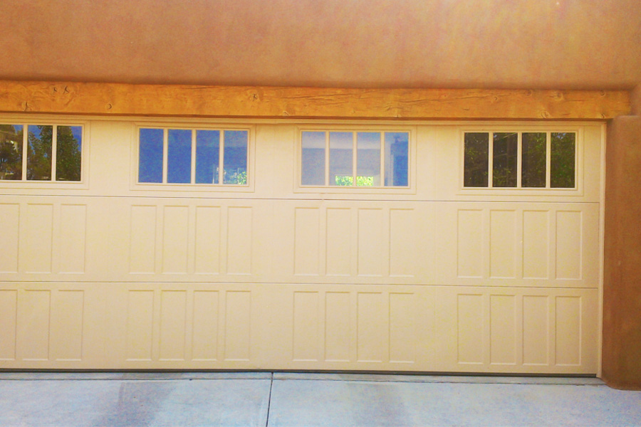 wide cream metal garage door with wooden beam and paneled windows