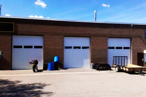 three white garage doors with windows on brick building