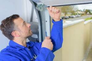 man with wrenches repairing garage door frame